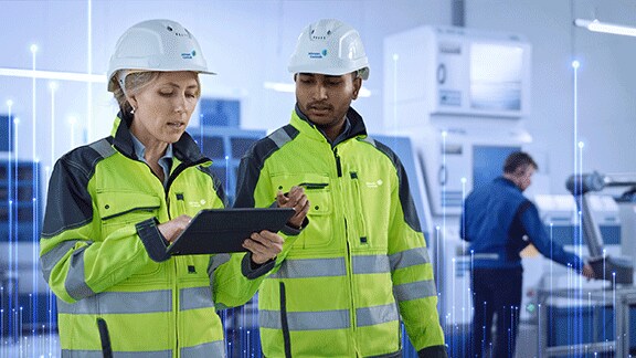 Two Johnson Controls technicians in safety gear using a tablet